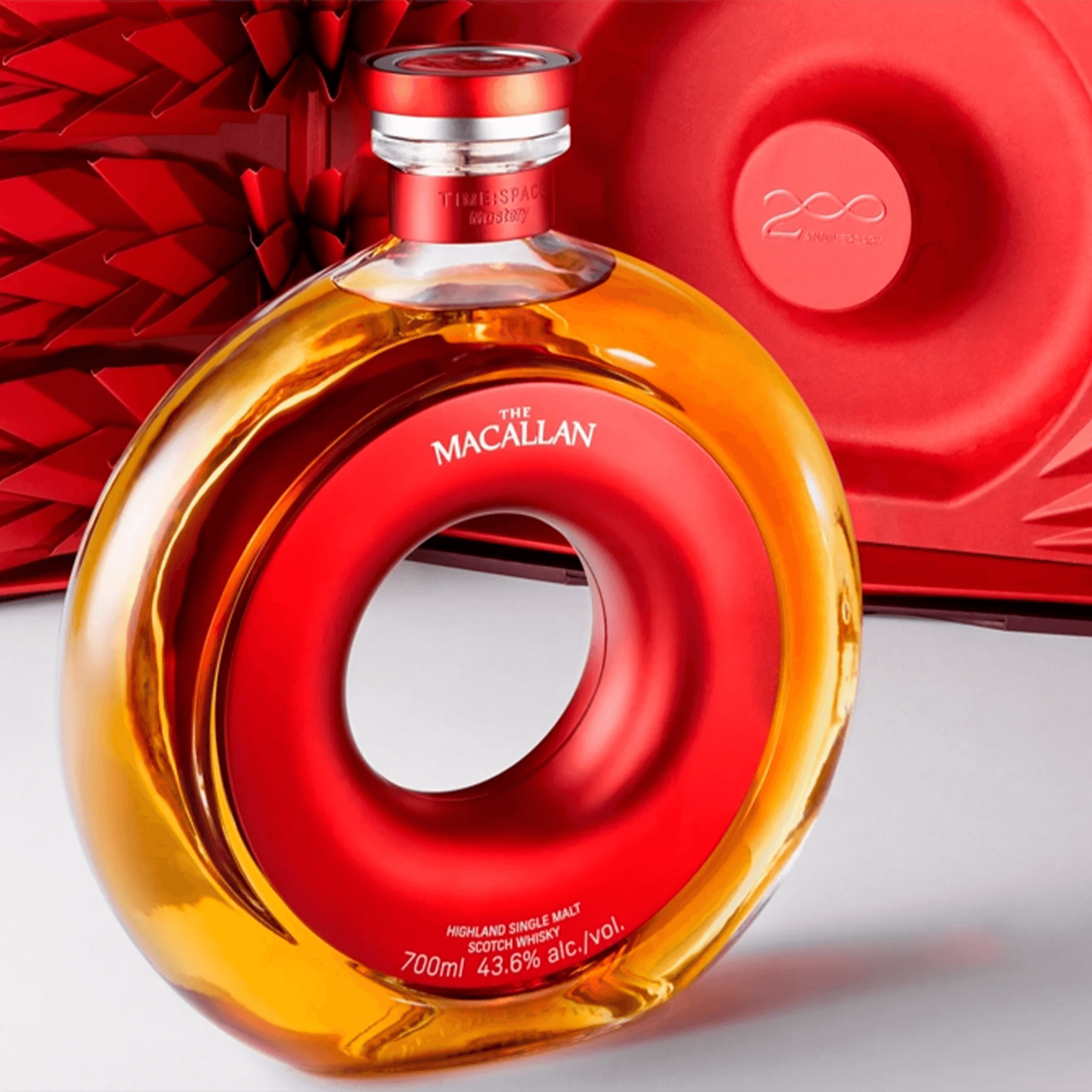 Macallan Time Space Mastery Single Malt Scotch Whisky bottle in unique circular design, showcasing amber whisky and red packaging.