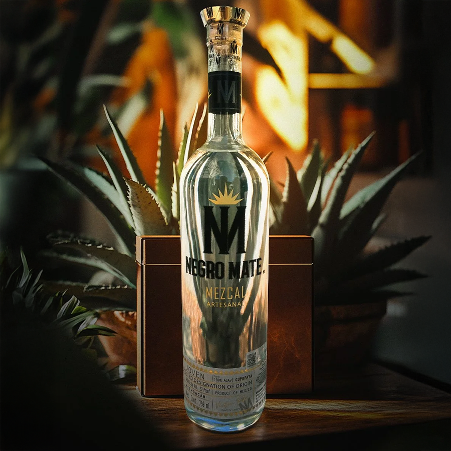 Negro Mate Mezcal bottle displayed among agave plants, showcasing its artisanal quality and robust character.