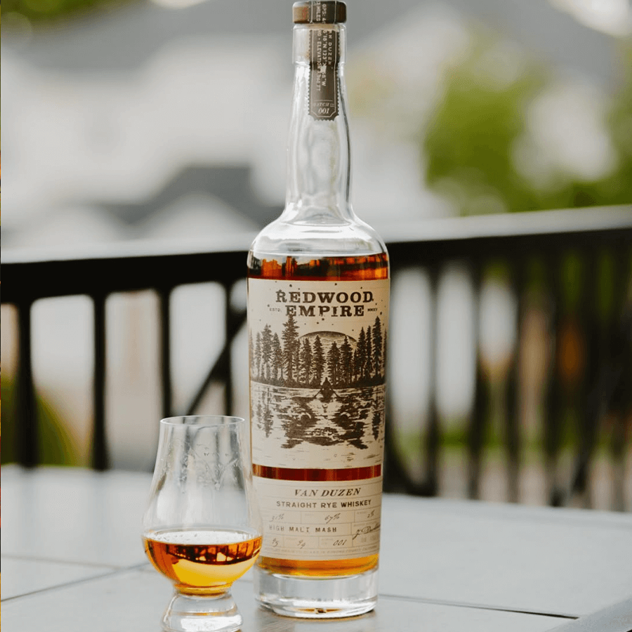 Bottle of Redwood Empire Van Duzen Straight Rye Whiskey with a glass, showcasing its rich amber color.
