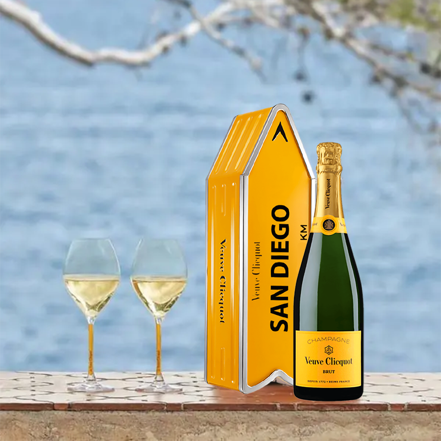 Veuve Clicquot Brut Yellow in San Diego container with two glasses of champagne against a blue background.
