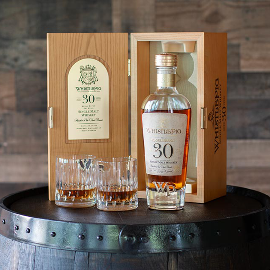 WhistlePig The Bigshebang 30 Year Single Malt Whiskey in a wooden box with glasses on a barrel.