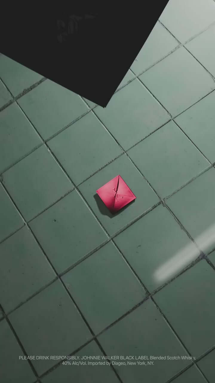 Johnnie Walker Black Label x Squid Games limited edition design with a red origami element on tiled floor.