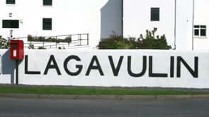 Lagavulin distillery sign featuring bold lettering against a white wall, emphasizing its iconic brand in Islay.