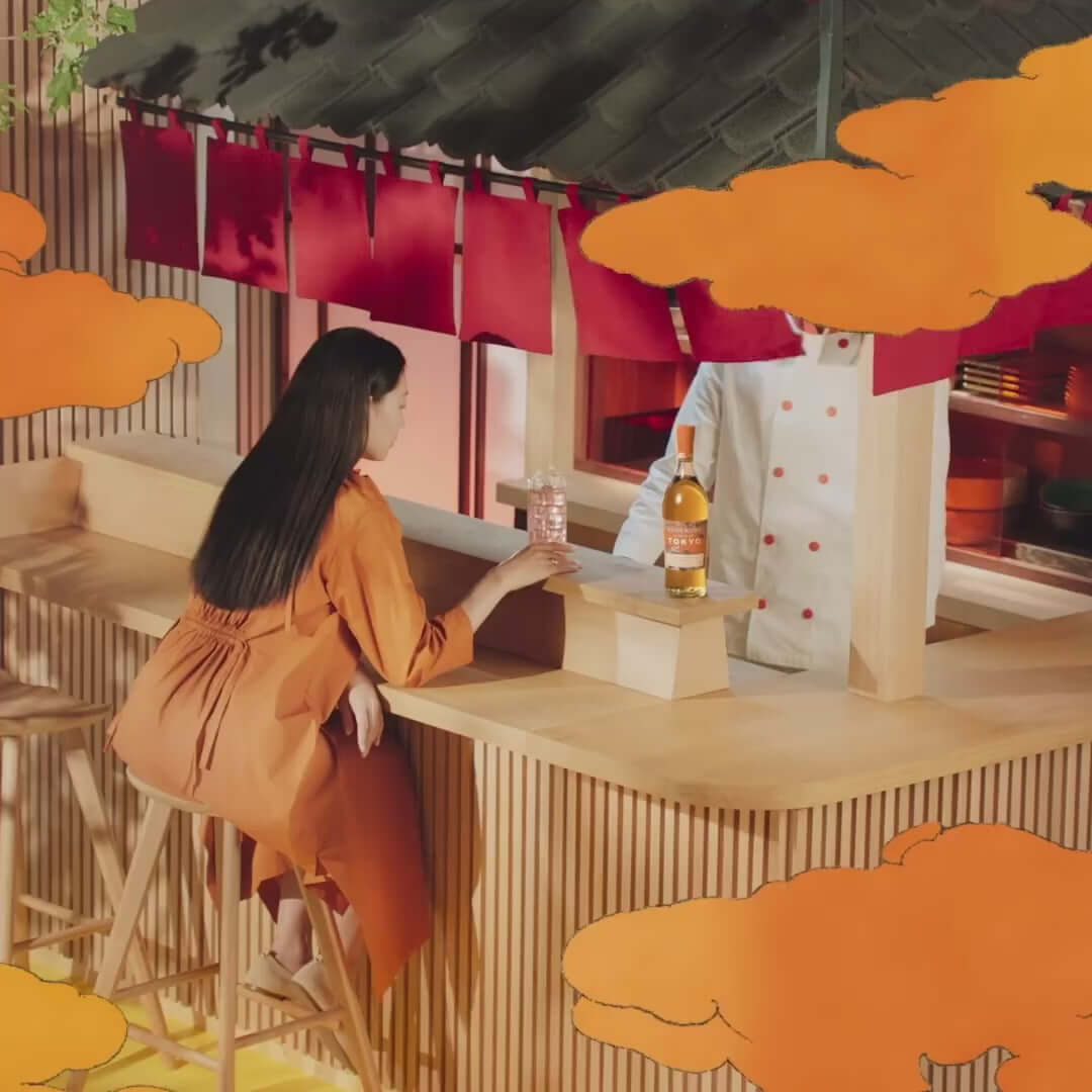 Woman in orange dress at a bar with Glenmorangie A Tale of Tokyo whisky and a chef in a vibrant setting.