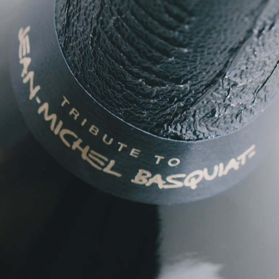 Close-up of Dom Pérignon bottle neck featuring 'Tribute to Jean-Michel Basquiat' label.