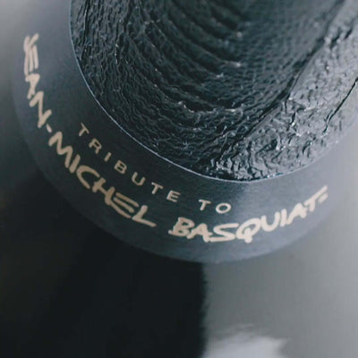 Close-up of Dom Pérignon bottle neck featuring 'Tribute to Jean-Michel Basquiat' label.