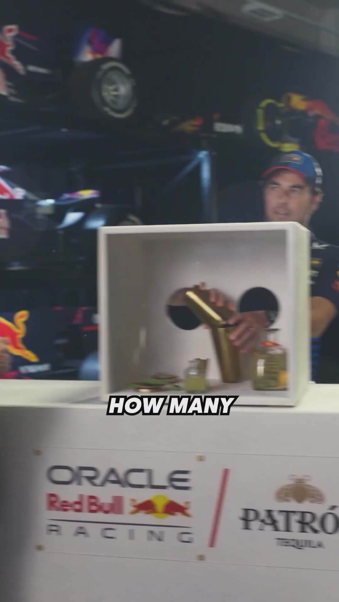Person interacting with Patrón Tequila at Oracle Red Bull Racing event, showcasing stylish bottle and brand logo.