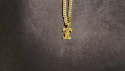 Gold necklace with pendant on a dark background showcasing intricate design and shine.