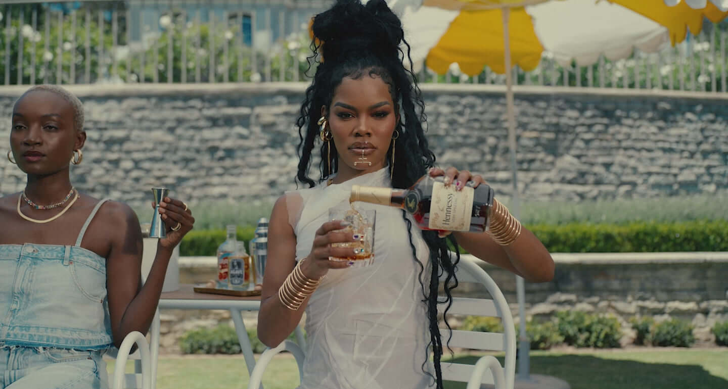 A woman pouring Hennessy Very Special V.S Cognac into a glass at an outdoor gathering.